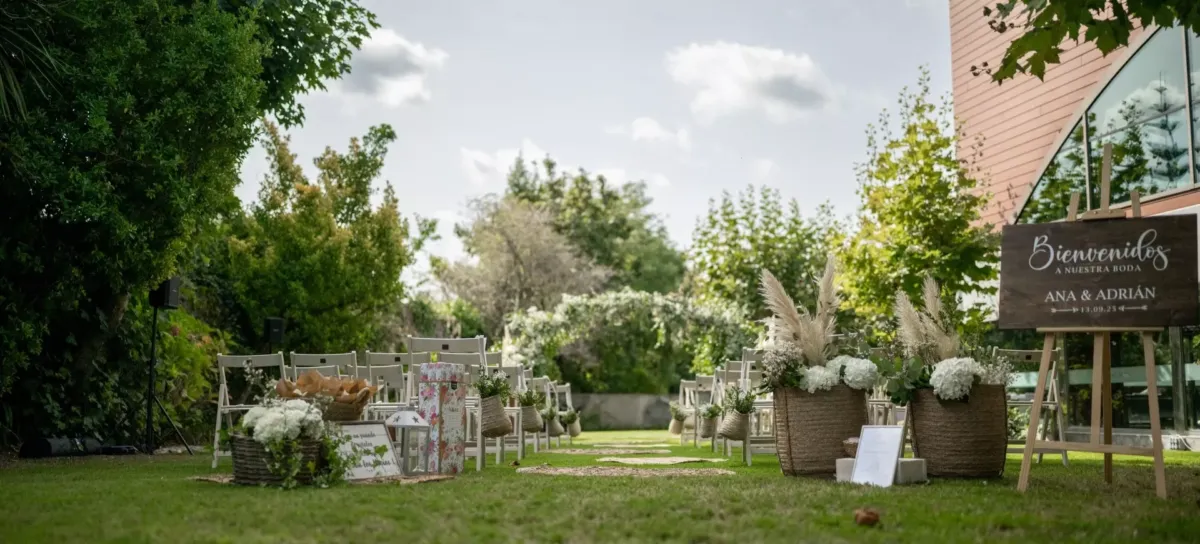 Sillas para invitados colocadas en un jardín frente a un altar con arco floral